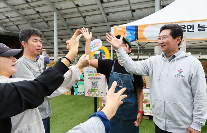 이상일 용인특례시장이 18일 시청 광장에서 열린 '책 속 한 줄 쓰Go, 농산물 받Go' 행사에서 시민들과 인사를 나누고 있다.